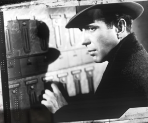 Image of Humphrey Bogart if front of a wall of mailboxes with surrounding graphics
